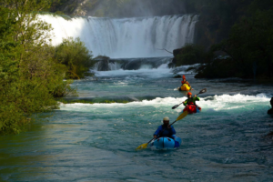 Tři jezdci na packraftech pod vodopádem na řece Zrmaja